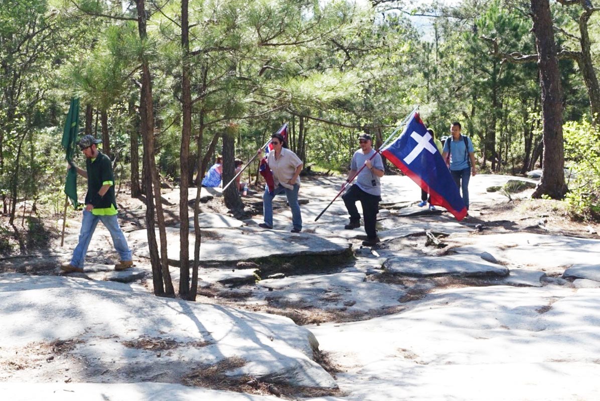 Men walking up Stone Mountain with confederate flags